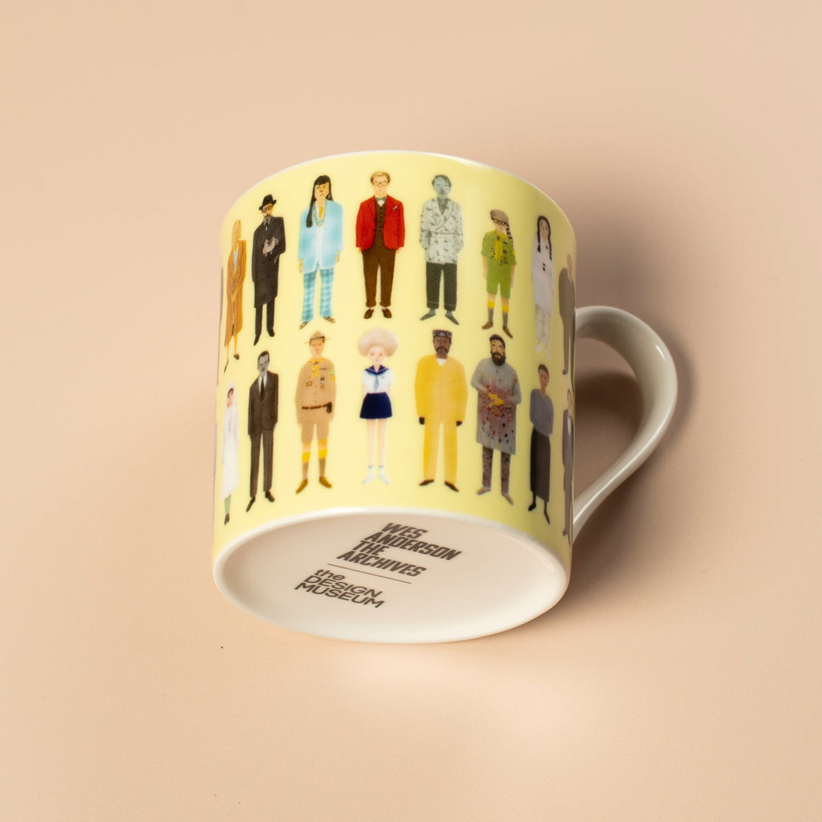 Yellow mug with illustrated characters on a beige background