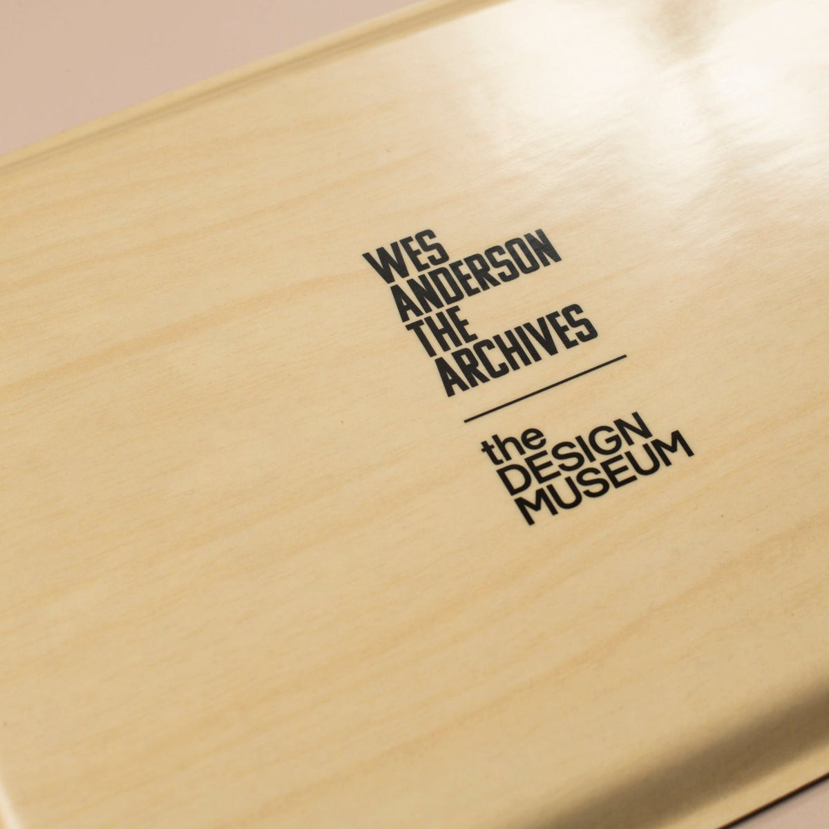 The back of a wooden tray with 'Wes Anderson The Archives' and 'The Design Museum' text on a beige background