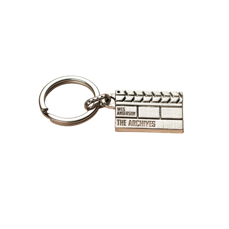 Silver clapperboard keychain with 'Wes Anderson: The Archives' logo on a white background