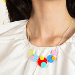 Woman wearing a multi-coloured acrylic necklace and white shirt