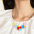 Woman wearing a multi-coloured acrylic necklace and white shirt