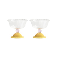 Two glass bowls with yellow bases and pink spheres on a white background