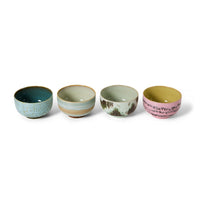 A set of 4 colourful abstract hand-painted ceramic noodle bowls in a row on a white background. 