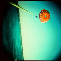 Vintage photo of an orange parasail in the air over the sea 