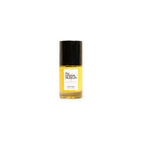 A small glass bottle of yellow nail polish with a black cap and a white label on a warm off-white background.
