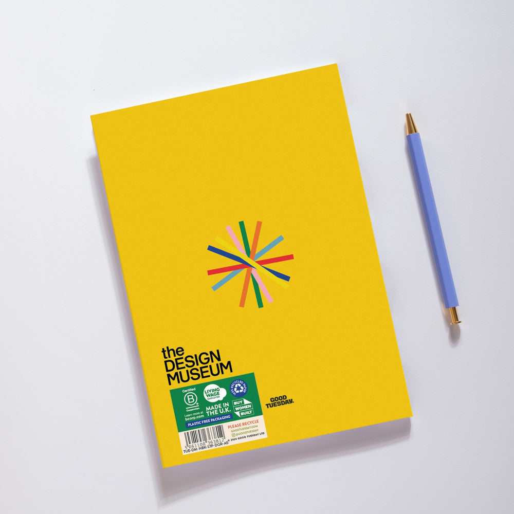 A bright yellow notebook with a colorful burst logo and 'the DESIGN MUSEUM' text, photographed on a white background next to a blue pen.