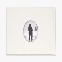 The back of a white book featuring a central oval frame containing a black silhouette of a person standing in a snowy white landscape, set against a clean white background.