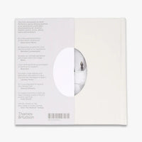 The back cover of a white book, featuring a white background with printed text, a barcode, and a circular cutout showing a minimalist scene of a person standing in a snowy landscape.