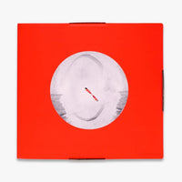 A square red box from above on a light gray background, featuring a large circular white-and-gray graphic in the center with a small red diagonal mark.