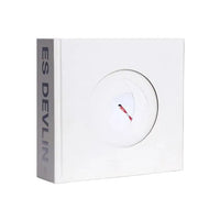 A white square book with a circular cutout on the front, showing a small red and black object inside, and the vertical text 'ES DEVILIN' printed on the side panel, set against a plain white background.
