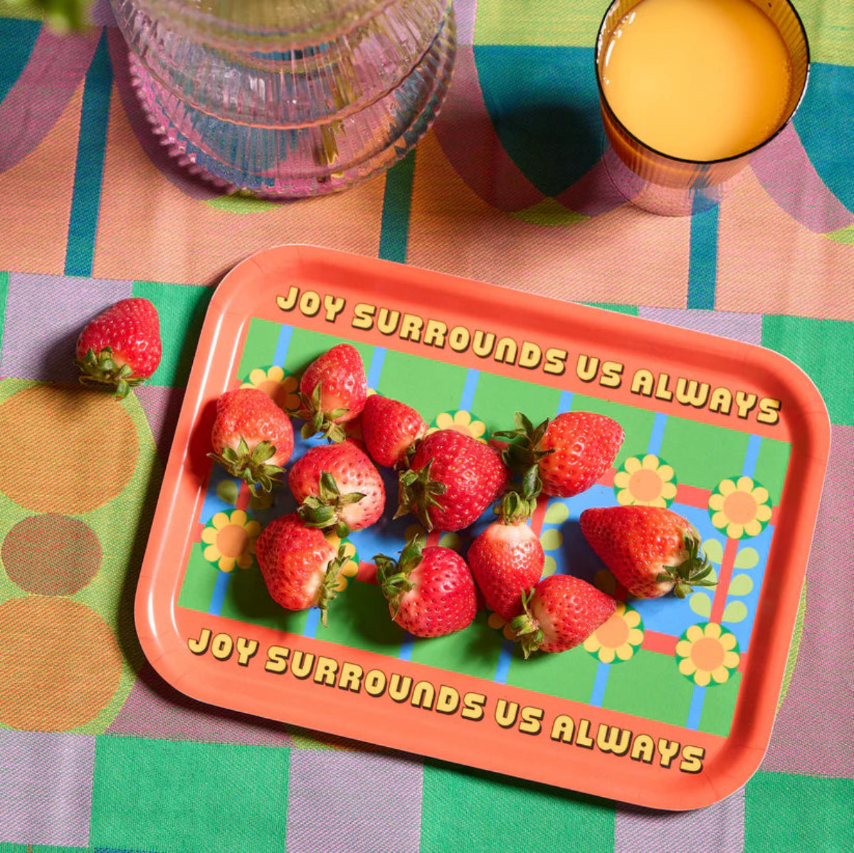 Colourful tray with strawberries and motivational quote on a patterned tablecloth
