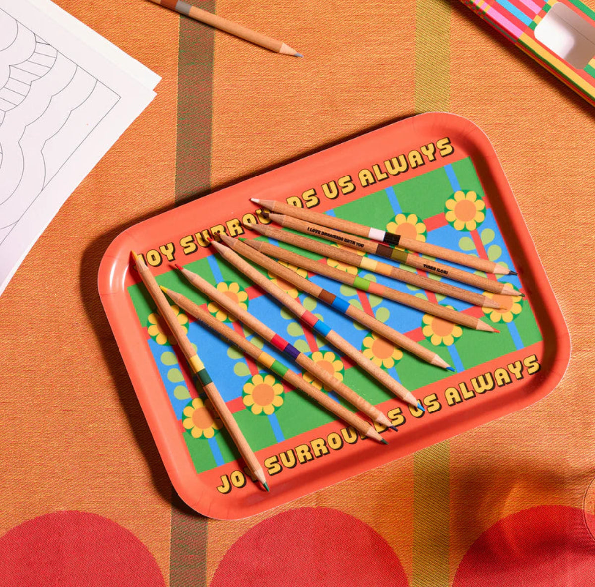 Colourful tray with pencils on a patterned surface