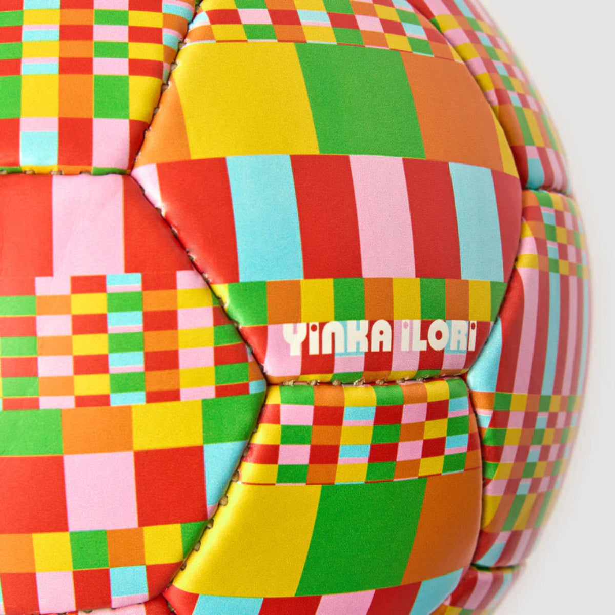 Colourful checkered football with 'Yinka Ilori' branding on a white background