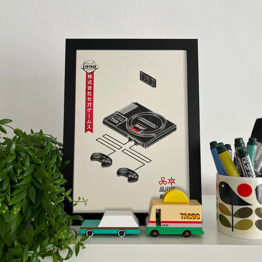 A framed vintage advertising inspired Playstation console print featuring a black console with red accents.