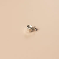 Small silver teacup charm on a beige background