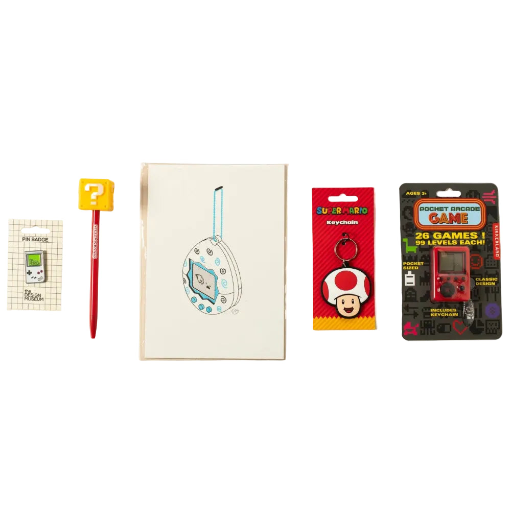 A collection of flat-layed items including a tamagotchi print, a pocket arcade game, a keyring, pen and a pin badge.