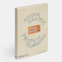 Book titled 'Designing Graphic Props for Filmmaking' with blue text on a beige grid background