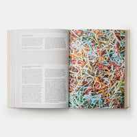 Open book with a picture of colourful shredded paper on one page and text on the other, on a white background.