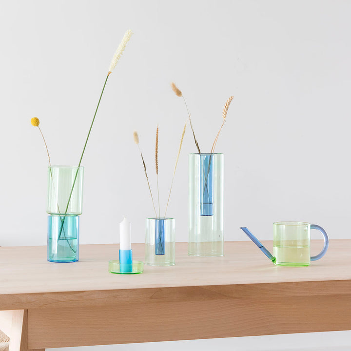 A collection of blue and green glass ornaments on a wooden table.