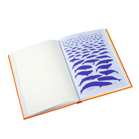 An open hardcover notebook or book with an orange cover, showing a printed page filled with purple whale silhouettes on the right side and blank lined pages on the left, photographed on a white background.