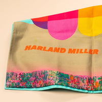 Colorful tea towel with 'Harland Miller' and text on a beige background