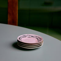 Stack of pink ceramic saucers on a green surface with a wooden bench in the background
