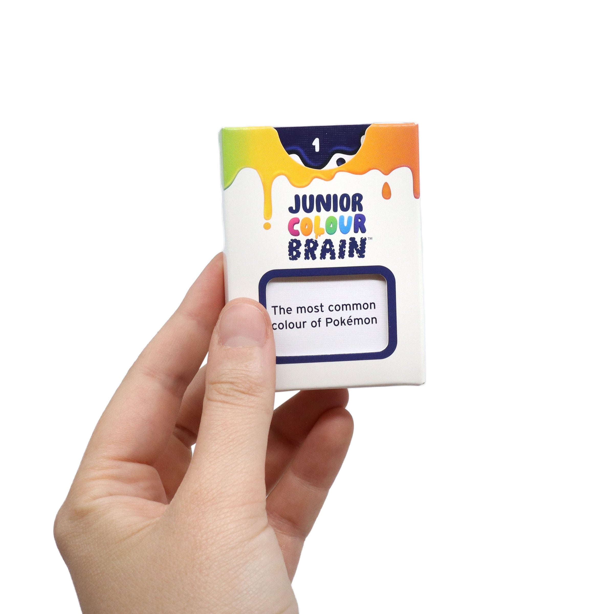 Hand holding a small box labeled 'Junior Colour Brain' with colorful design on a white background