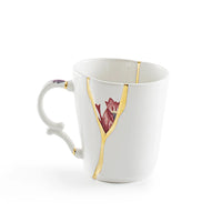 White ceramic mug with floral design and gold kintsugi accents on a white background