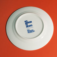 The back of a white plate with blue text on a red background