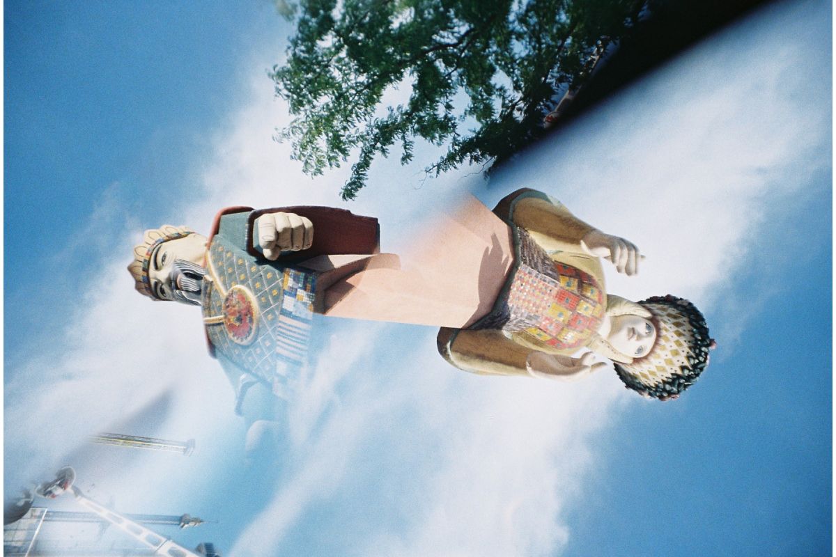 A photograph of two totem pole figures against a blue sky