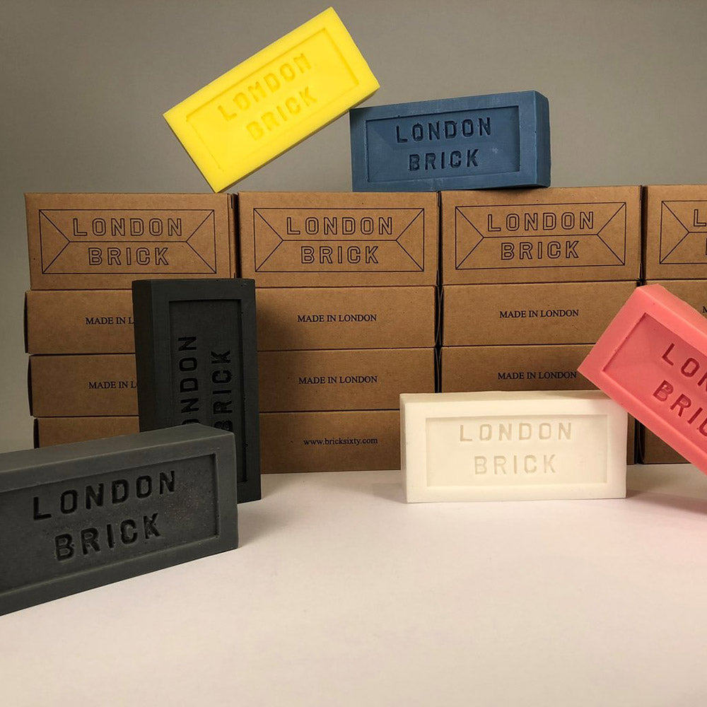 Various colours of London Brick soap blocks displayed around a stack of brown cardboard packaging.