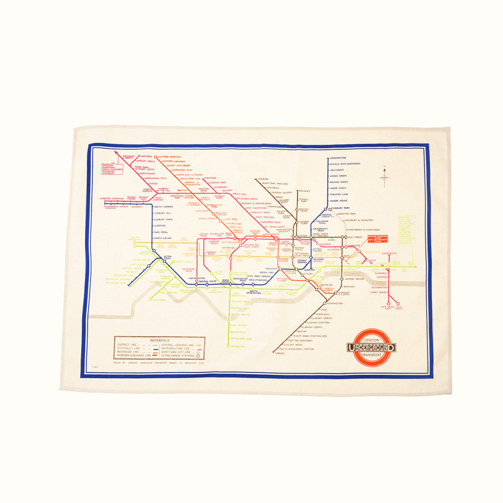 A beige tea towel with a colourful illustration of the London Underground Tube map feauring the London Undergound Transport logo.