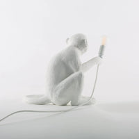 White monkey lamp holding a light bulb on a white background