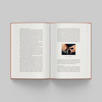 Open page of More Than Human catalogue featuring text and a small image on a gray background