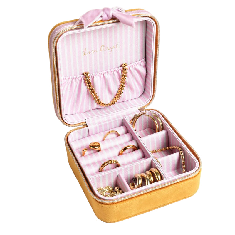 Open jewelry box with gold jewelry on a beige background