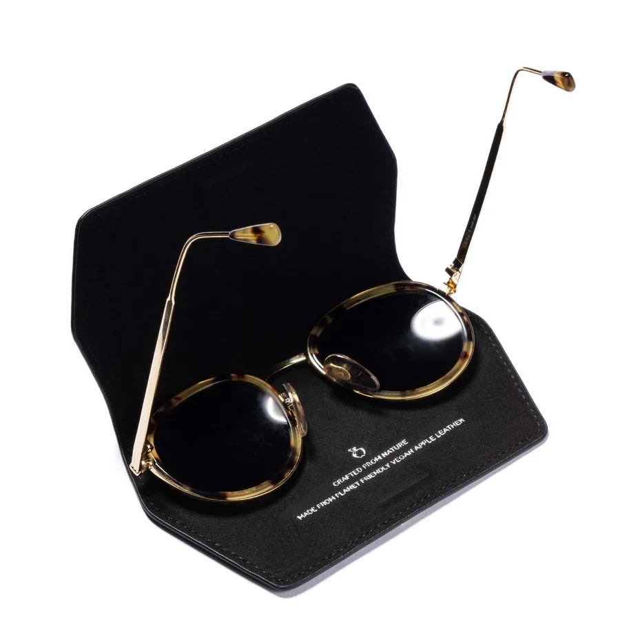 Gold-framed sunglasses with in a black glasses case on a white background.