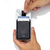 A hand holding a white smartphone while another hand pulls a card out of  a black wallet attached to the phone. 