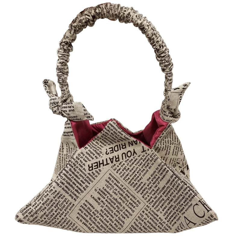 Handbag made from newspaper with a visible brand tag on a white background