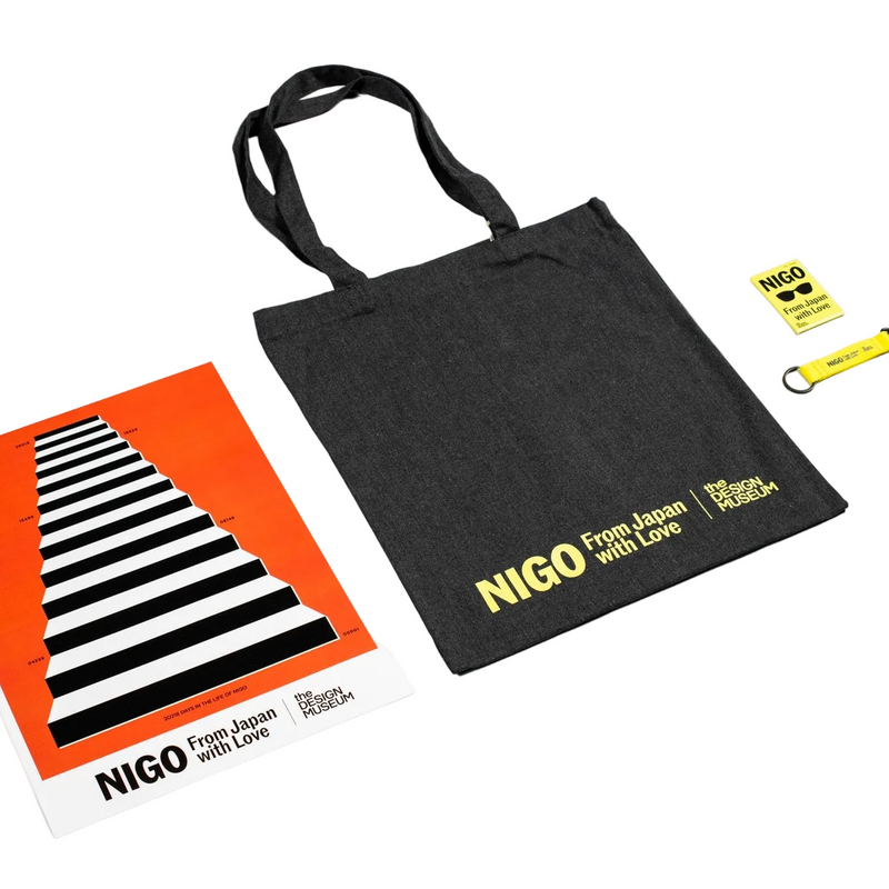 Black tote bag with 'NIGO' branding, orange and white striped poster, and yellow keyring and magnet on a white background.