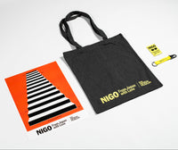Black tote bag with 'NIGO' branding, orange and black striped poster, and yellow keychain and magnet on a white background.
