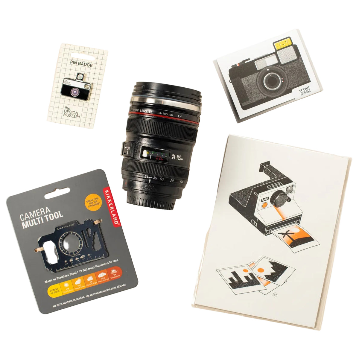 A camera multi-tool set arranged on a light beige background, alongside a black camera lens mug, a small card, and a camera print
