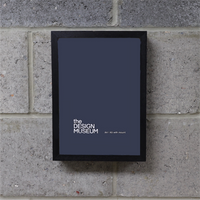 A grey poster in a black picture frame on a brick wall.