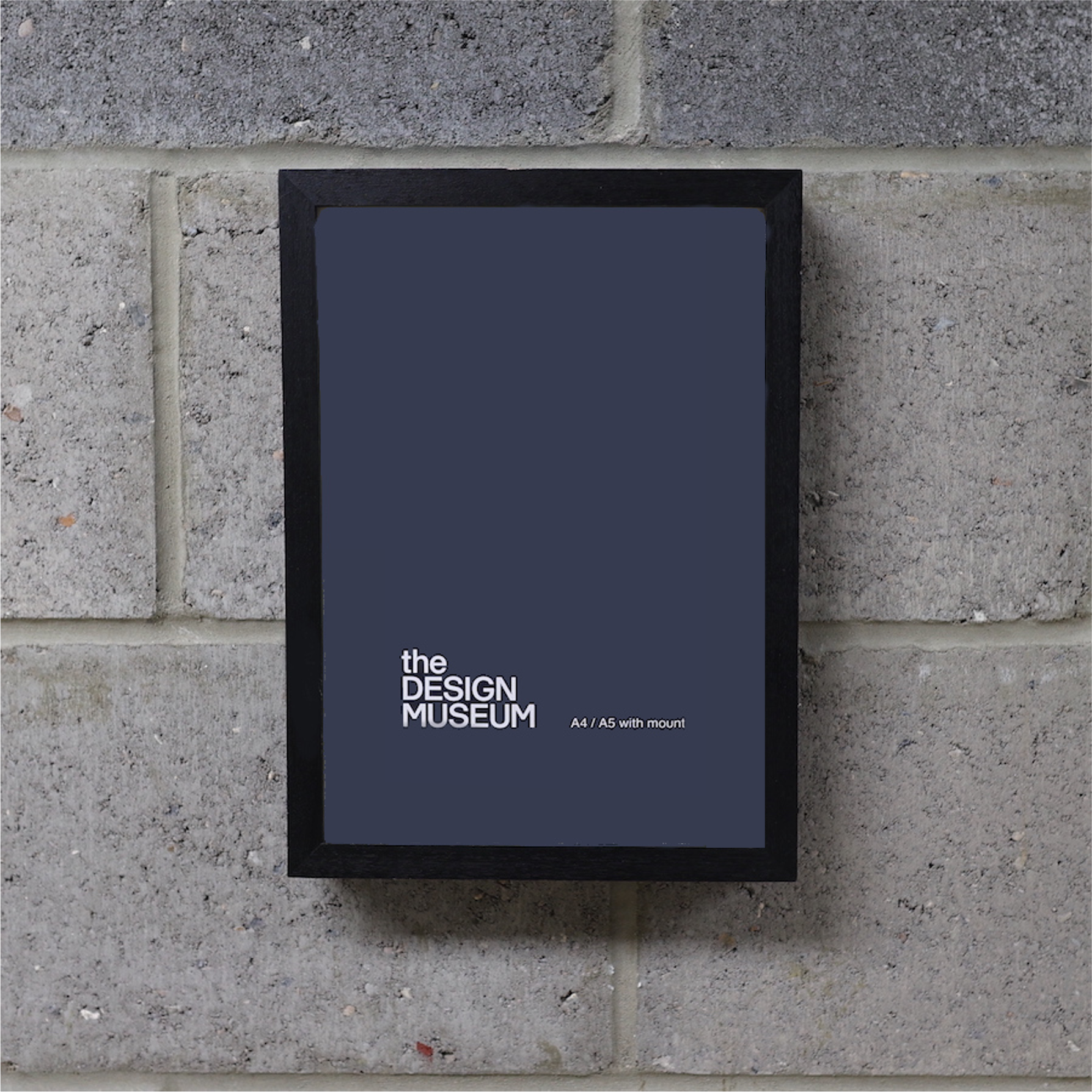 A grey poster in a black picture frame on a brick wall.