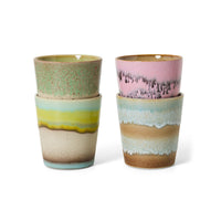 A set of four stacked colourful abstract ceramic mugs on a white background.