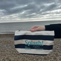 Splash Zip Pouch Navy Blue Stripe hold by a hand on real life background, seaside
