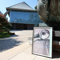 Framed picture of a watch in front of a building with a statue