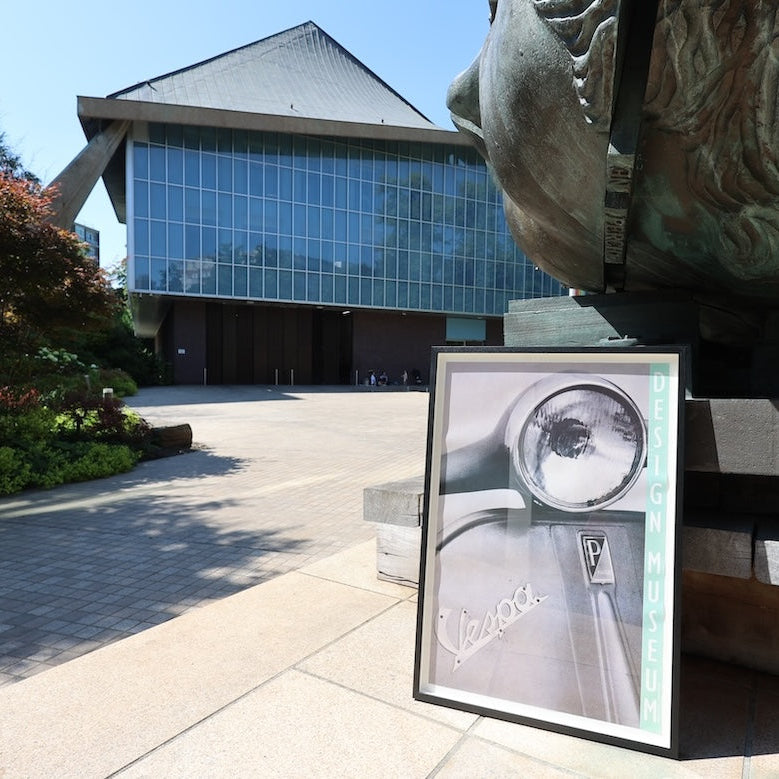 Framed picture of a watch in front of a building with a statue