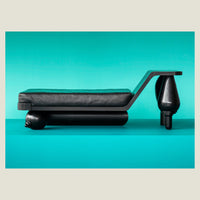 Black modern reclined sofa on a teal background