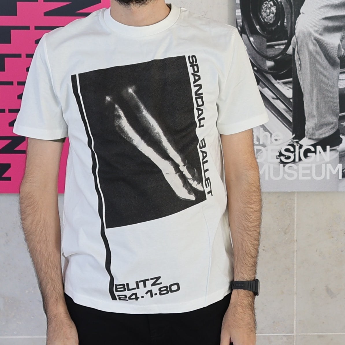 Person wearing a white t-shirt with black graphic design in front of a colorful background