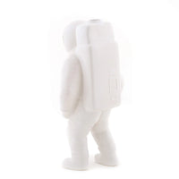 The back of a white ceramic astronaut vase on a white background